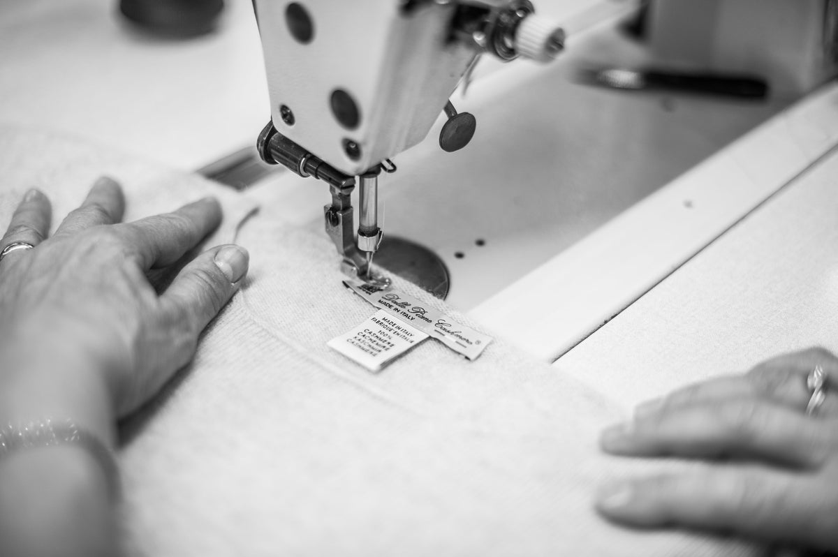 Le mani al lavoro sulla rimagliatrice nel laboratorio di Prato